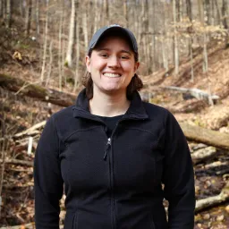 An image of Natalie Griffiths in a black shirt standing in the woods.