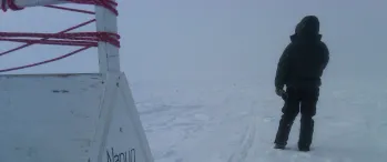 a man standing in the snow next to a sign