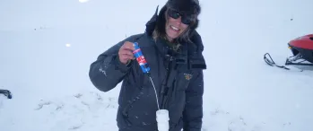 a person standing in the snow beside a pipe