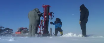 a group of people standing next to a machine in the snow