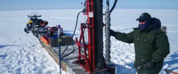 a man standing next to a machine in the snow