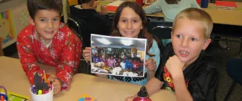 a group of young children sitting at a table in a classroom