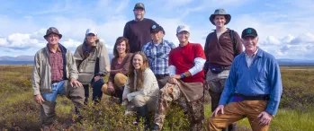 a group of people standing on top of a grass covered field