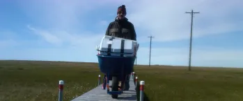 a man pushing a loaded wheel barrow down a wooden walkway