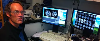 a man sitting in front of two computer monitors