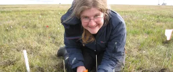 a woman kneeling down in the grass