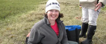 a woman sitting on the ground holding a soil core