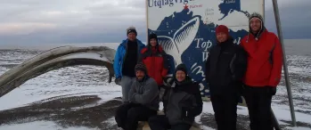 a group of people standing in front of a 'Welcome to Barrow' sign