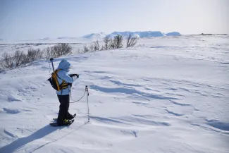 A researcher measures snow depth at the Kougarok field site