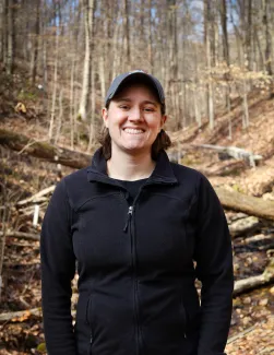 An image of Natalie Griffiths in a black shirt standing in the woods.